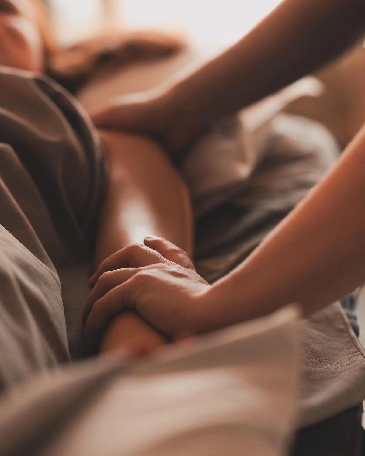 Hands resting on a mother's back during bodywork